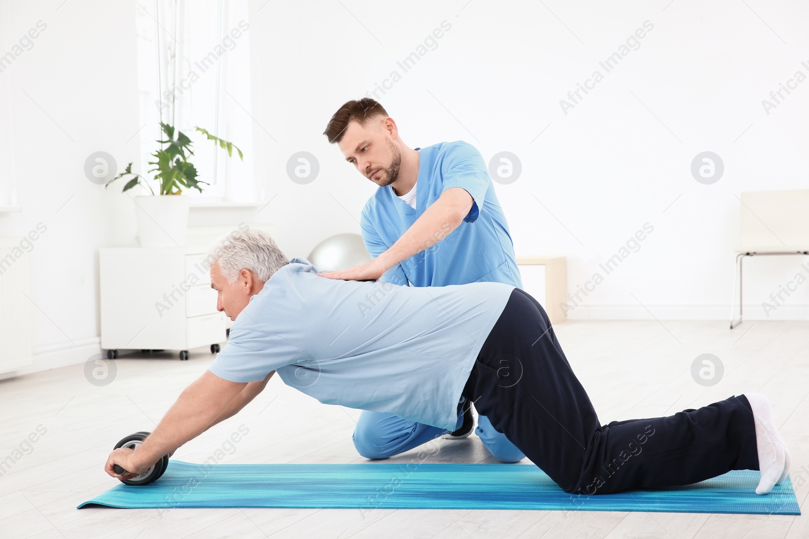 Photo of Young physiotherapist working with senior patient in clinic