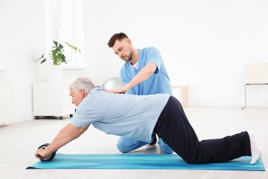 Young physiotherapist working with senior patient in clinic