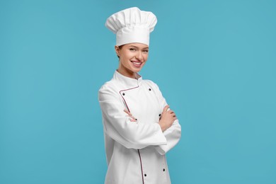 Photo of Happy chef in uniform on light blue background