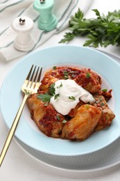 Photo of Delicious stuffed cabbage rolls served with sour cream on white table