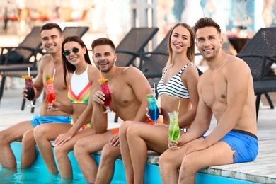 Photo of Happy young friends with refreshing cocktails near swimming pool