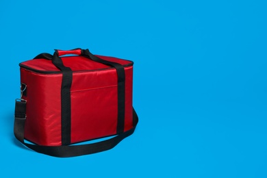Photo of Modern red thermo bag on light blue background. Space for text