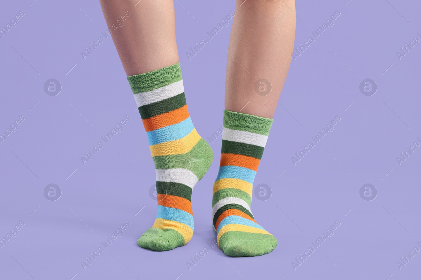 Photo of Woman in stylish colorful socks on violet background, closeup