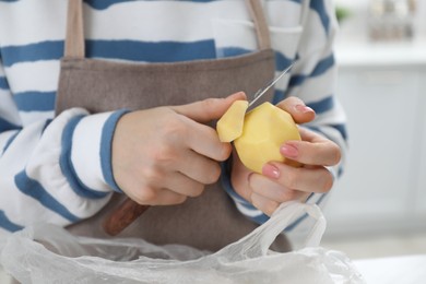 Woman peeling fresh potato with knife at white marble table indoors, closeup