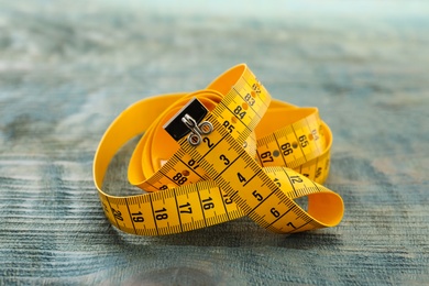 Yellow measuring tape on light blue wooden table, closeup