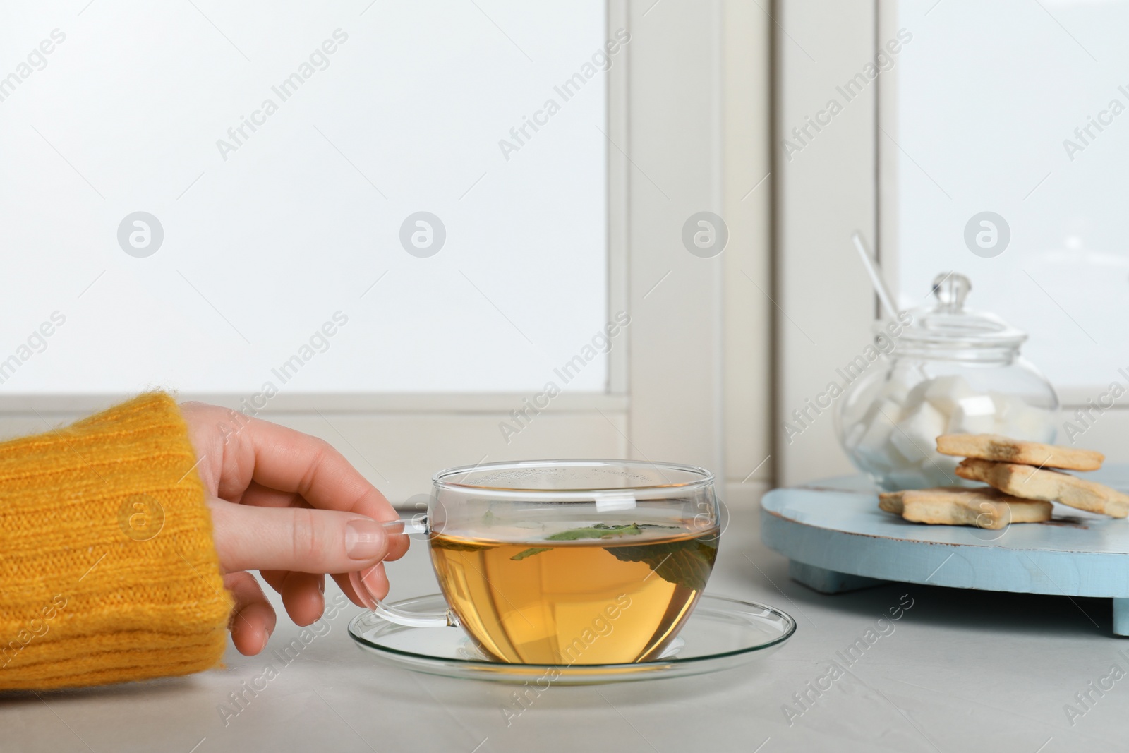 Photo of Woman with cup of tea at window, closeup. Winter drink