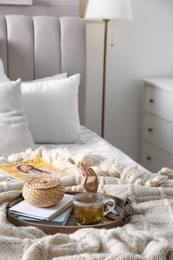 Photo of Stylish tray with different interior elements and tea on bed indoors