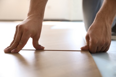 Worker installing laminated wooden floor indoors, closeup