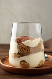 Delicious tiramisu in glass on wooden table, closeup