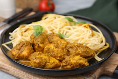 Photo of Delicious pasta and chicken with curry sauce served on table, closeup