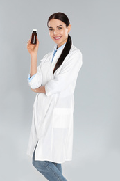 Photo of Professional pharmacist with syrup on light grey background