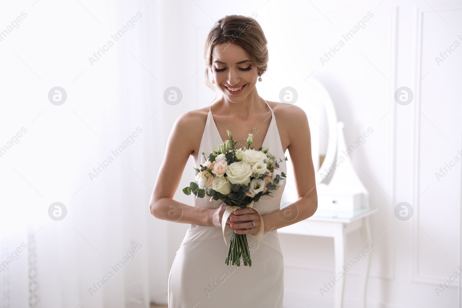 Photo of Young bride with beautiful wedding bouquet in room
