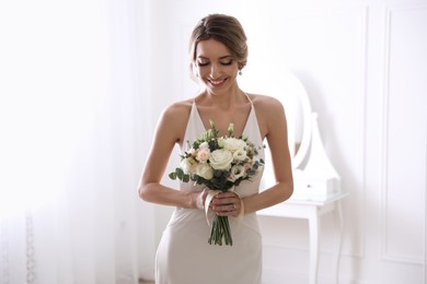 Young bride with beautiful wedding bouquet in room