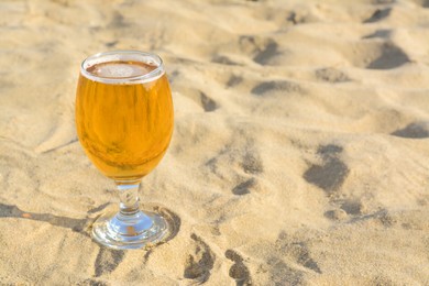 Photo of Glass of cold beer on sandy beach. Space for text