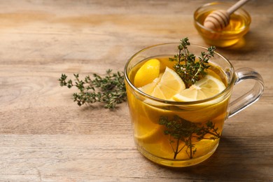 Fresh thyme tea with pieces of lemon on wooden table, closeup. Space for text