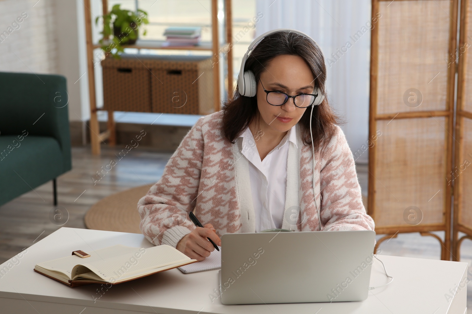 Photo of Woman with modern laptop and headphones learning at home