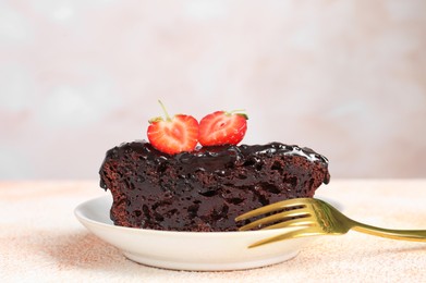 Photo of Piece of chocolate sponge cake with strawberry on beige textured table