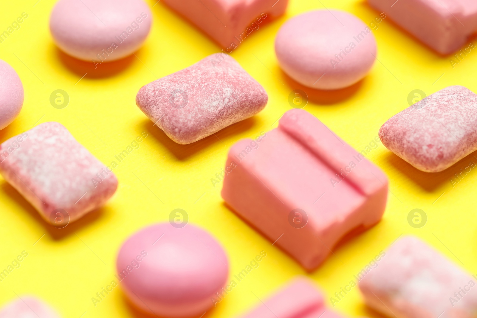 Photo of Pink bubble gums on yellow background, closeup