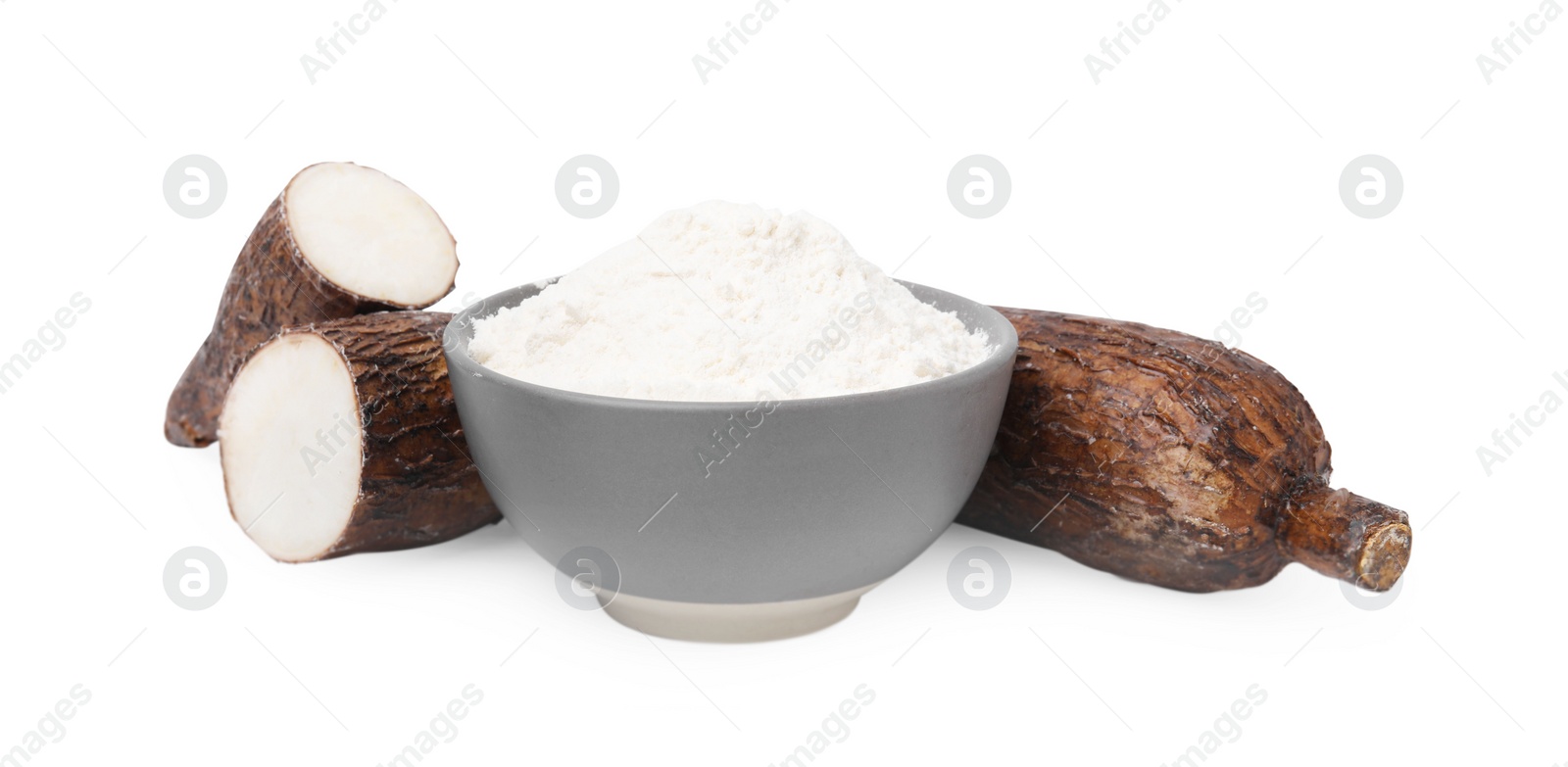 Photo of Bowl with cassava flour and roots isolated on white