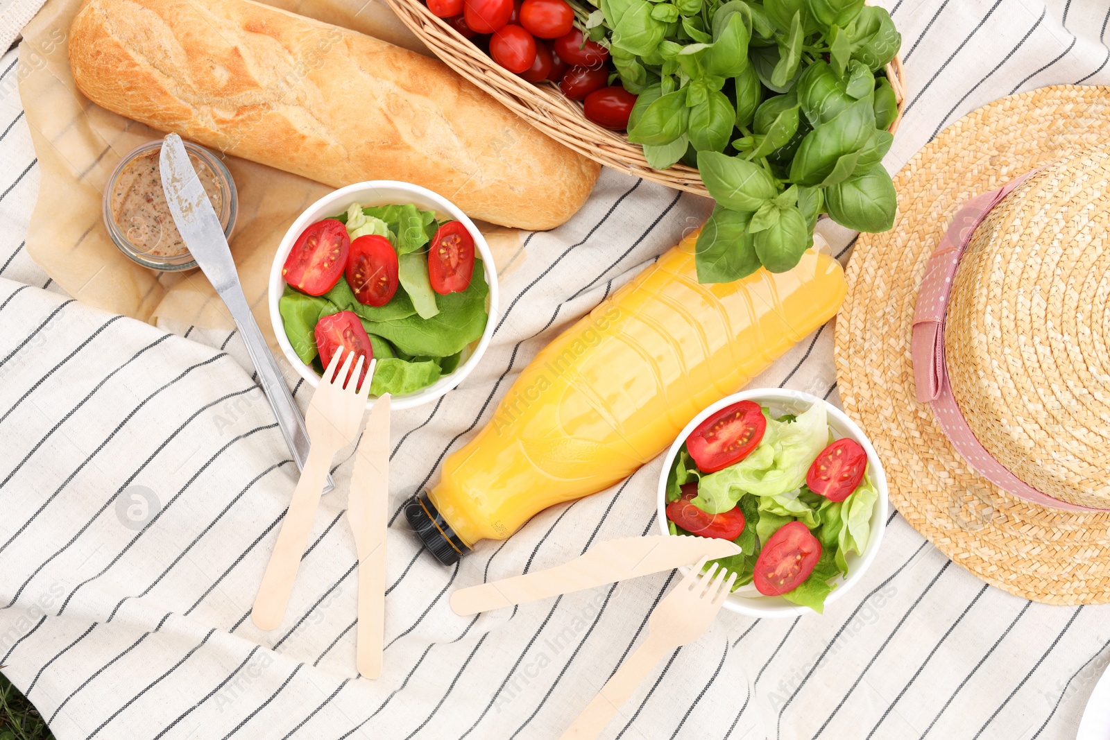 Photo of Juice and food on white striped blanket, flat lay. Picnic season