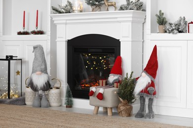 Photo of Cute Scandinavian gnomes and other Christmas decorations in room with near fireplace