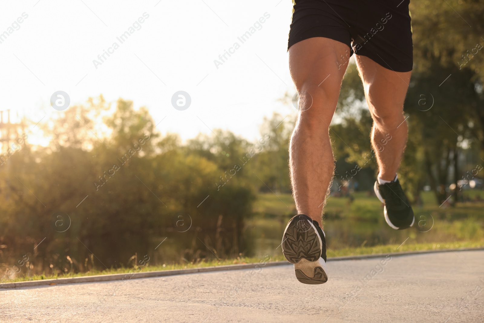 Photo of Man running near pond in park on sunny day, closeup. Space for text