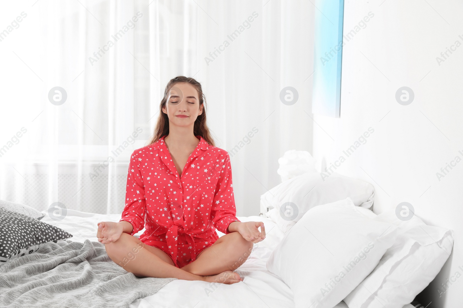 Photo of Young woman meditating on bed at home. Morning fitness