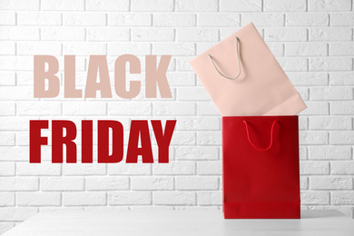 Image of Colorful shopping bags and text BLACK FRIDAY against white brick wall