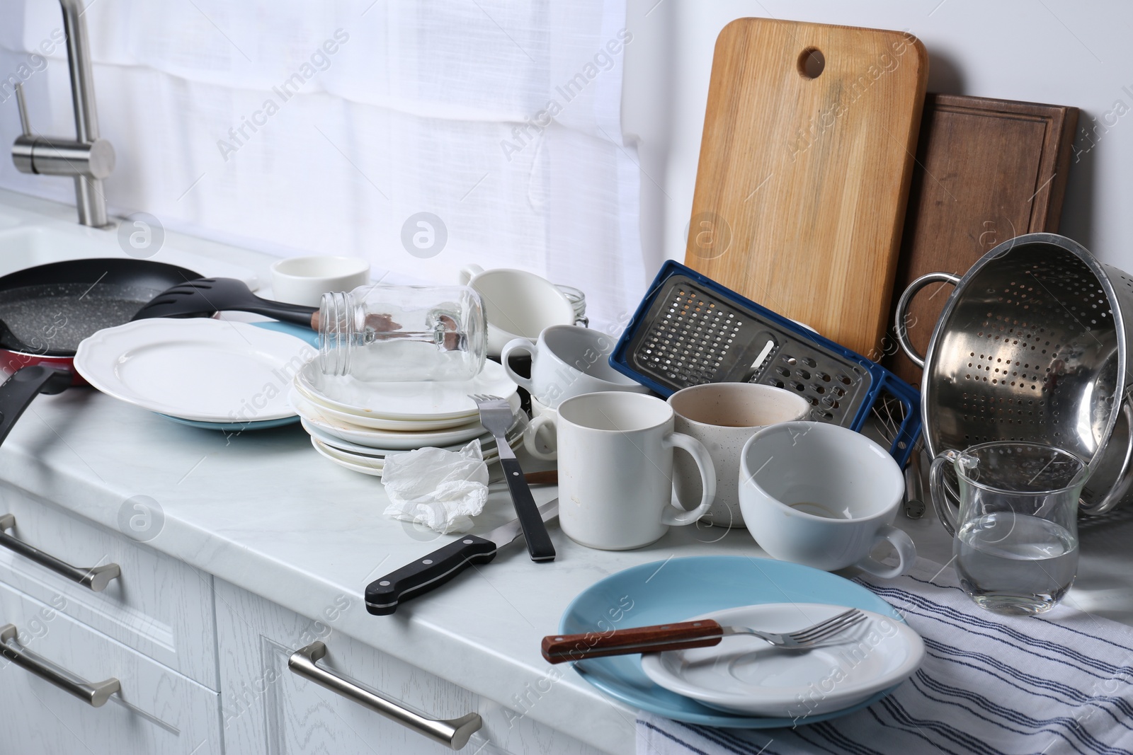 Photo of Many dirty utensils and dishware on countertop in messy kitchen