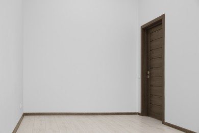 Empty renovated room with white walls and black door