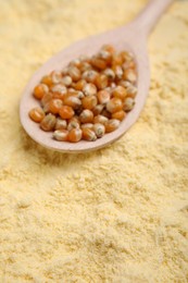 Spoon with corn grains on flour, closeup