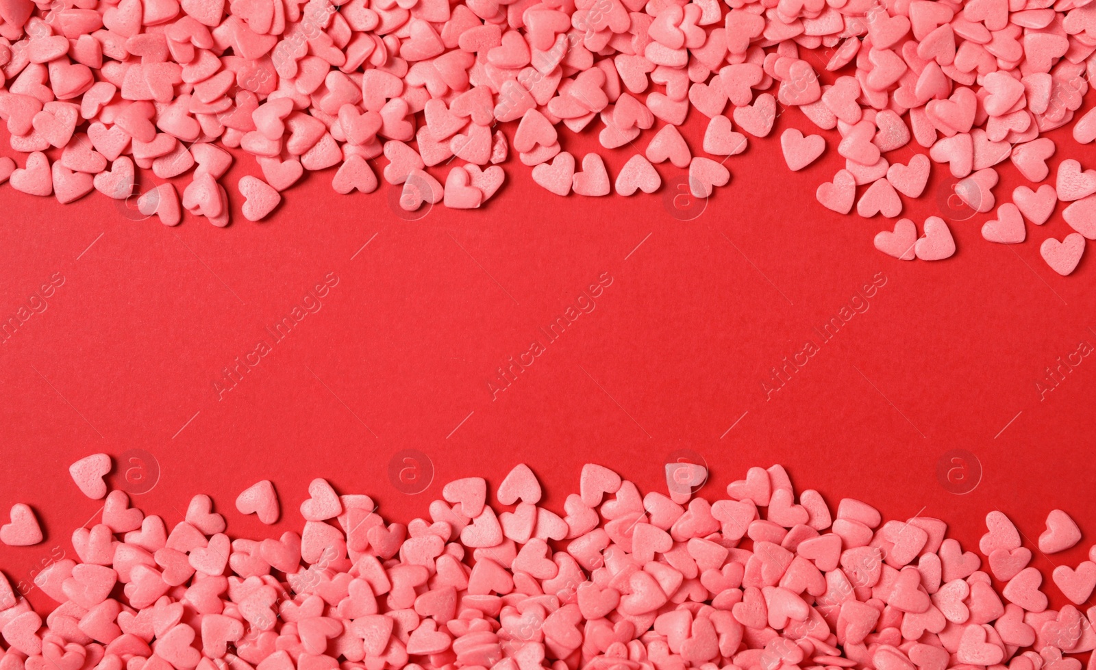 Photo of Bright heart shaped sprinkles on red background, flat lay. Space for text