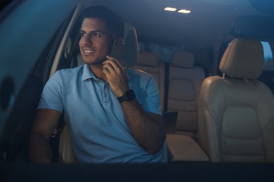 Handsome man talking on phone in modern car