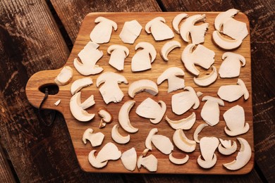 Photo of Board with slices of mushrooms on wooden table prepared for natural dehydration, top view