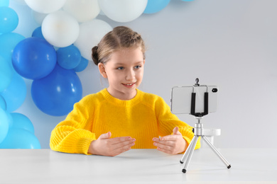 Photo of Cute little blogger recording video at table