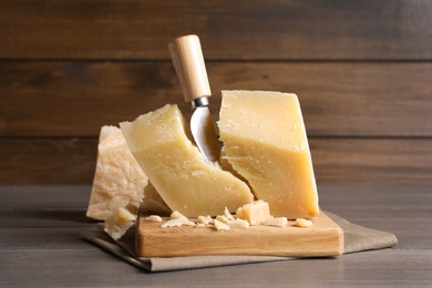Photo of Parmesan cheese with knife on wooden table