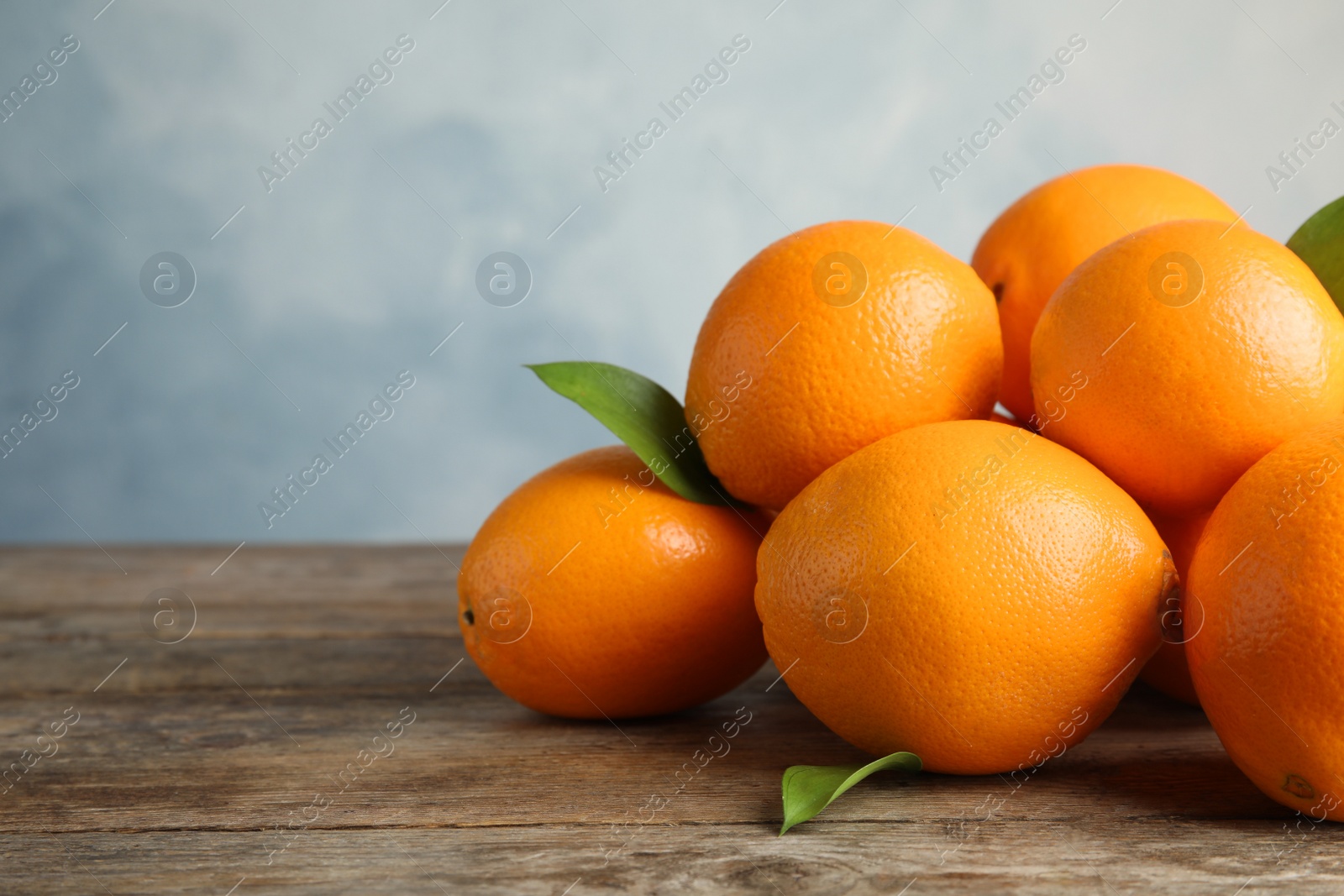 Photo of Fresh oranges with leaves on wooden table. Space for text