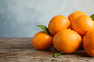 Photo of Fresh oranges with leaves on wooden table. Space for text