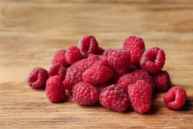 Photo of Heap of delicious ripe raspberries on wooden table, closeup