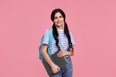 Smiling student with laptop on pink background