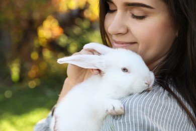 Happy woman with cute rabbit outdoors on sunny day, closeup. Space for text
