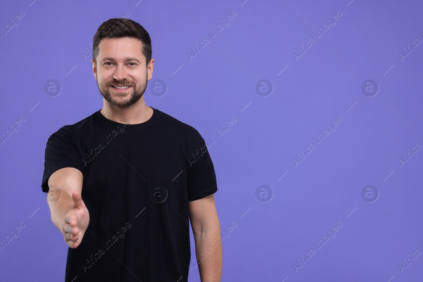 Photo of Happy man welcoming and offering handshake on purple background. Space for text