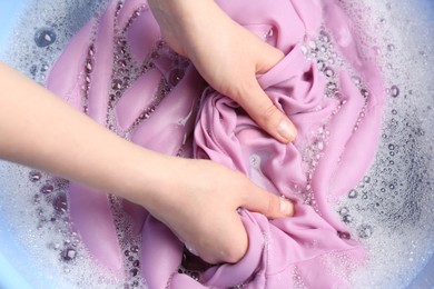 Photo of Top view of woman hand washing color clothing in suds, closeup