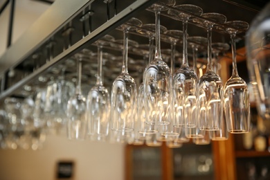 Many clean glasses on metal rack in restaurant