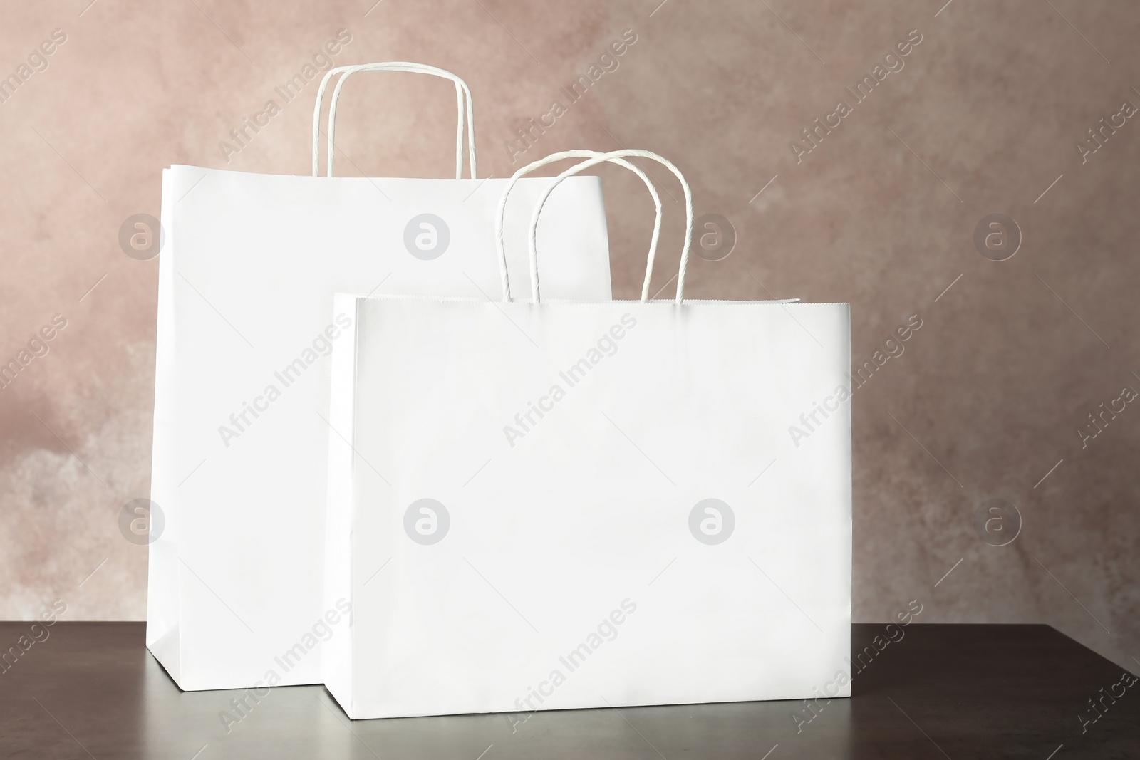 Photo of Mockup of paper shopping bags on table against color background