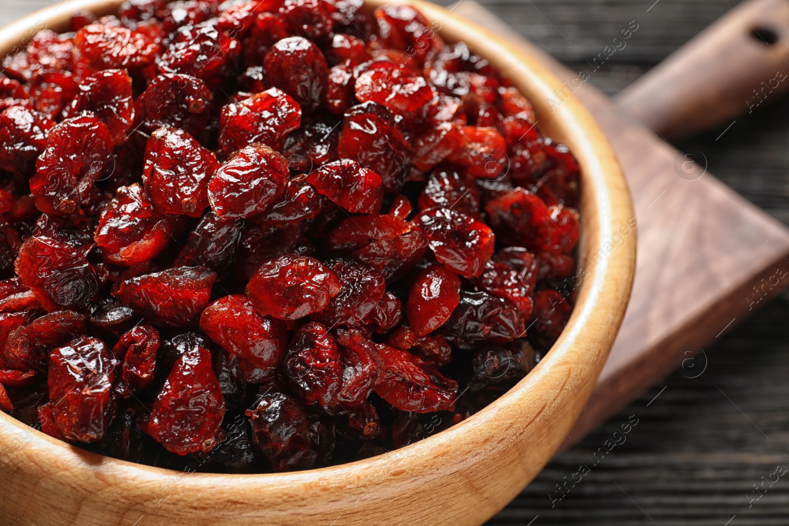 Photo of Bowl with cranberries on wooden table, closeup. Dried fruit as healthy snack