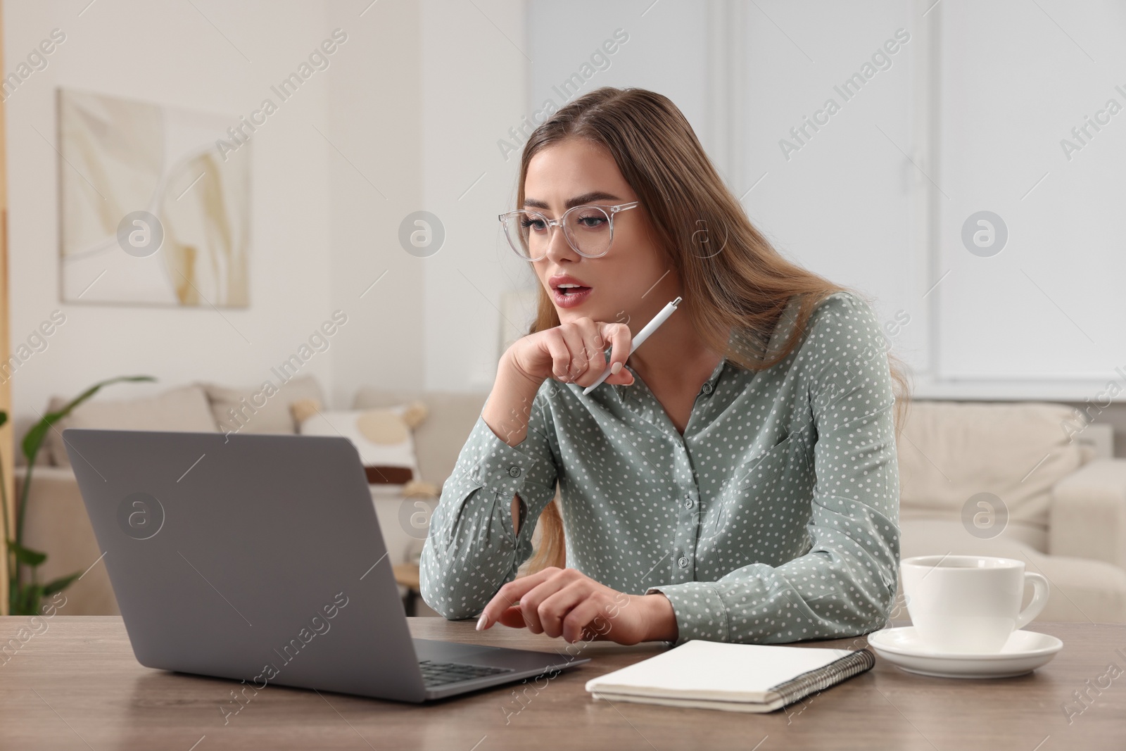 Photo of Beautiful woman with laptop at wooden table in room