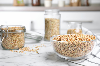 Photo of Uncooked green buckwheat grains on white marble table