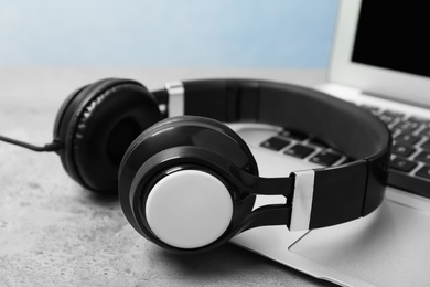 Photo of Modern headphones and laptop on table, closeup