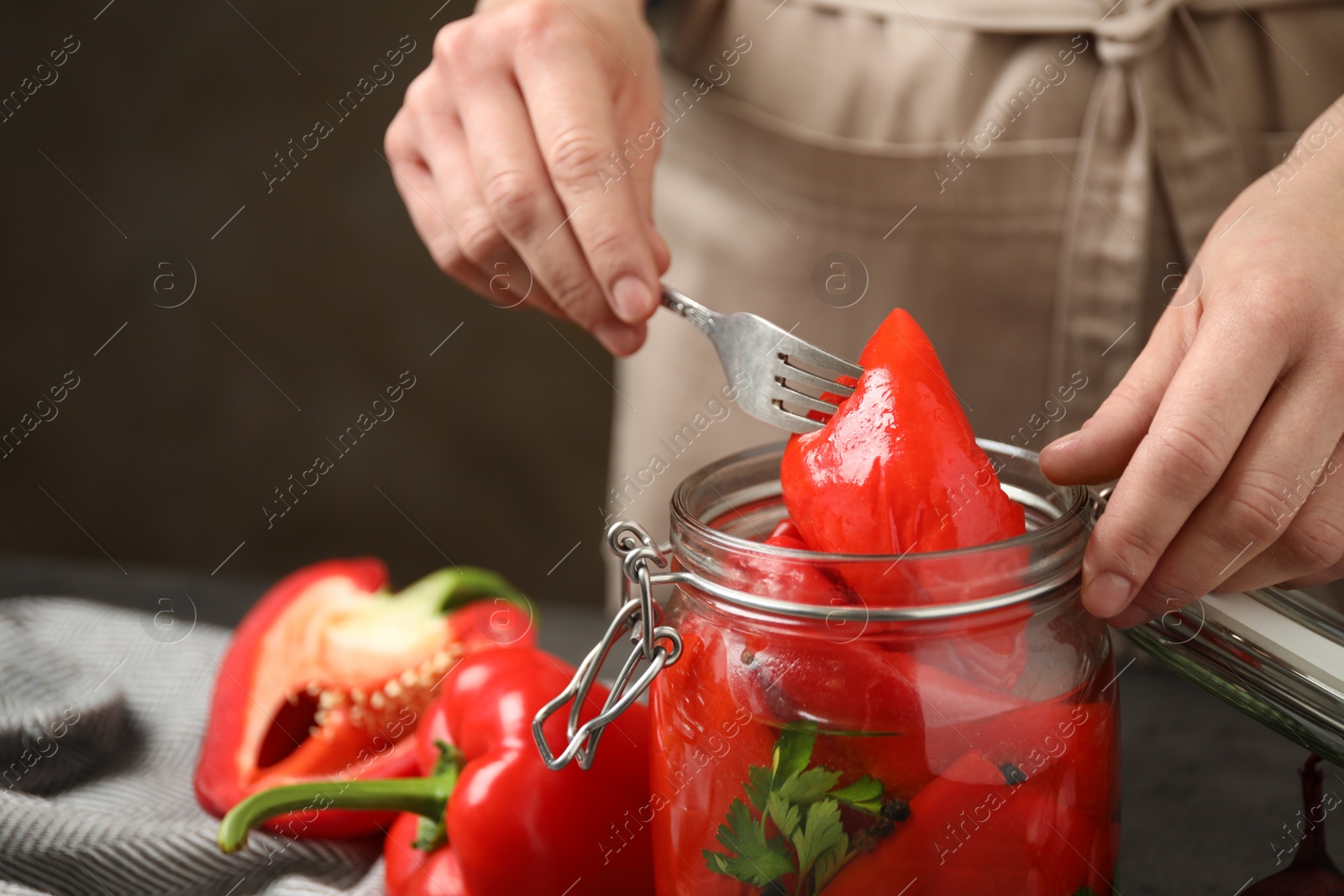 Photo of Woman with jar of pickled peppers at table, closeup